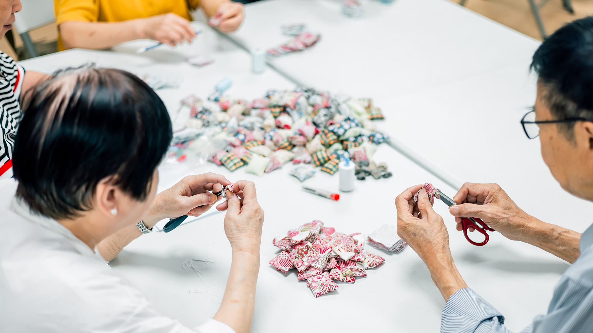 华懋集团与致力推动长者就业的社会企业银杏馆携手合作，邀请长者以一针一线缝製「抓子」纪念品。